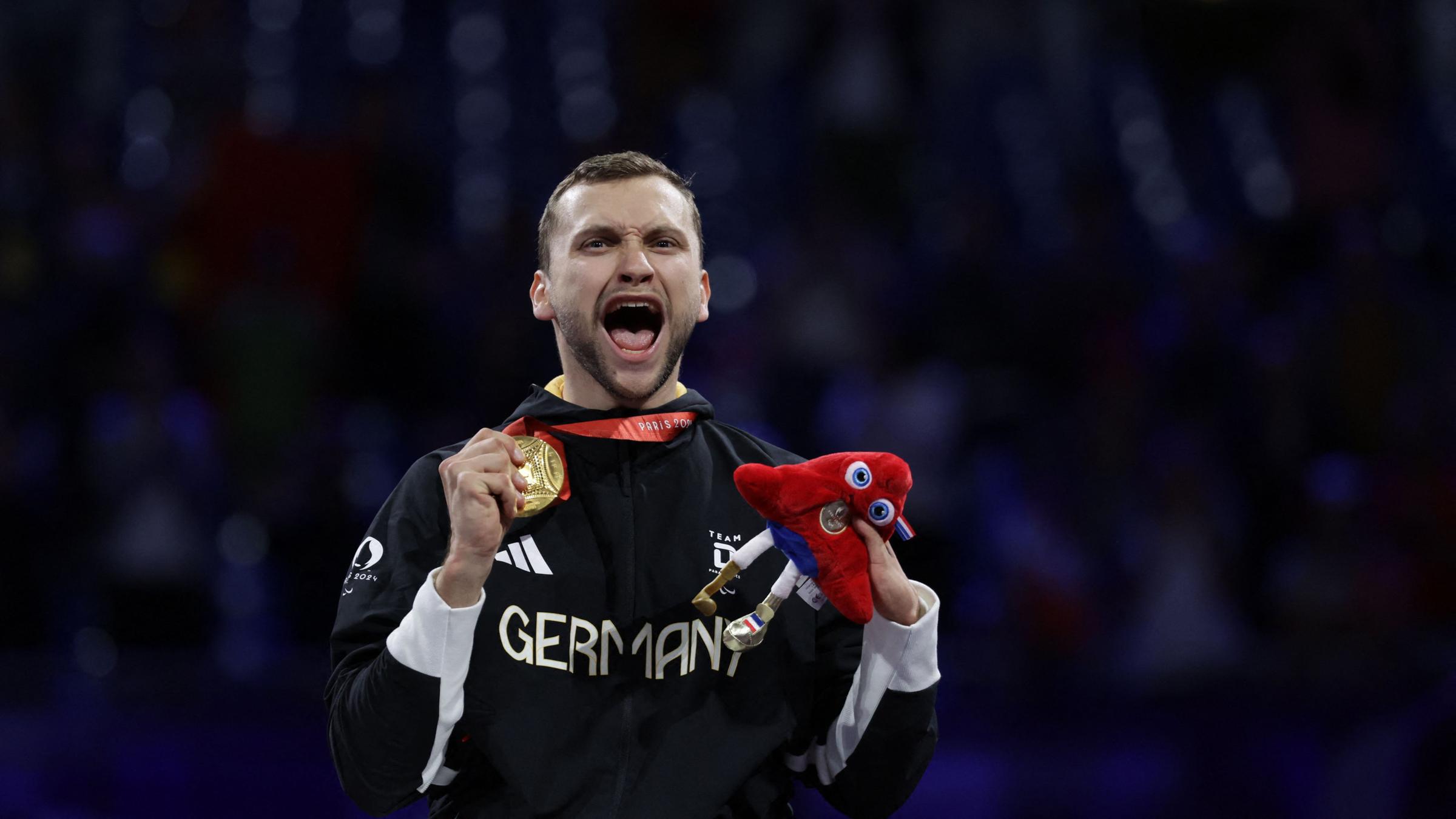 Maurice Schmidt zeigt lächelnd seine Goldmedaille
