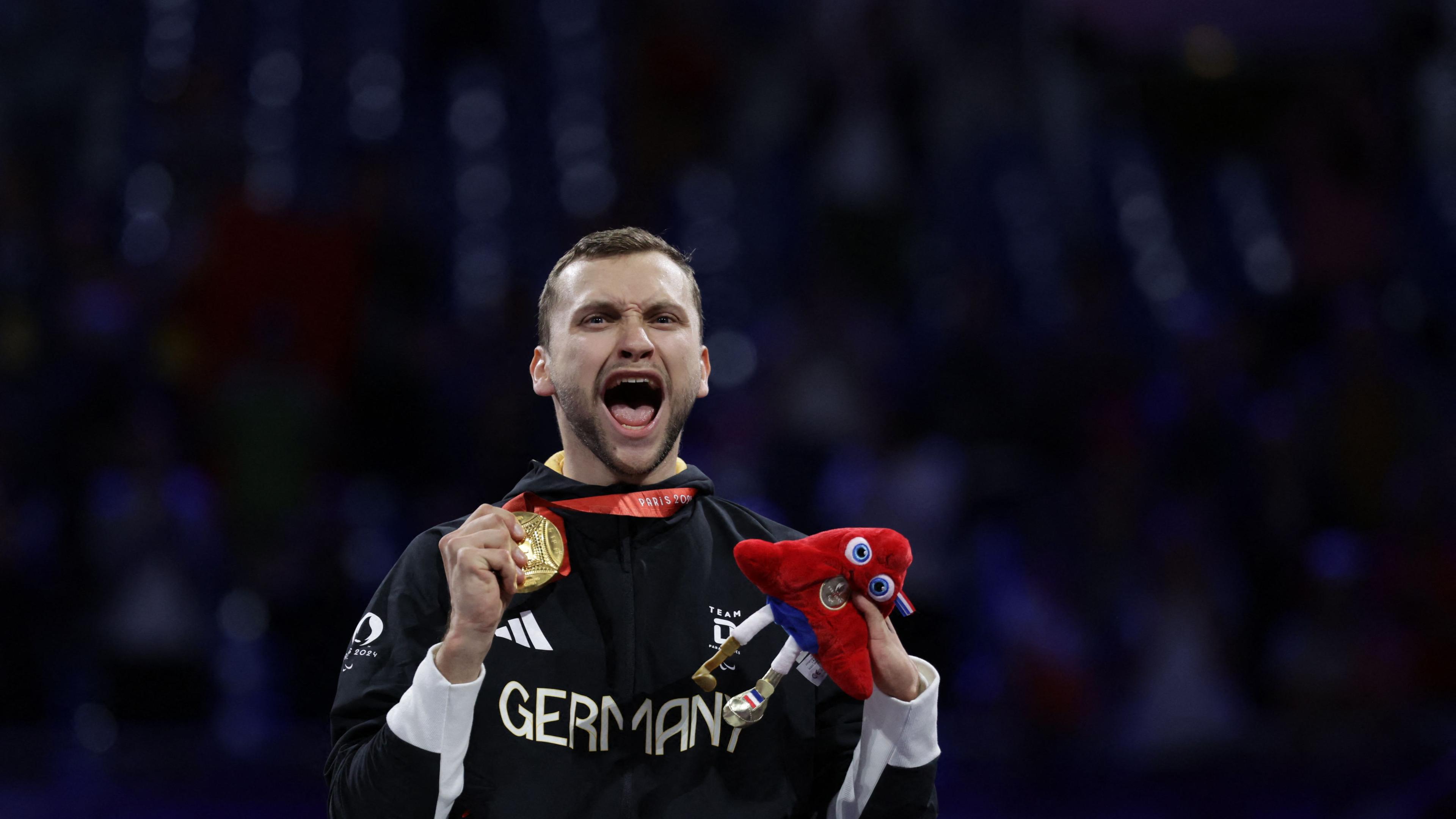 Maurice Schmidt zeigt lächelnd seine Goldmedaille