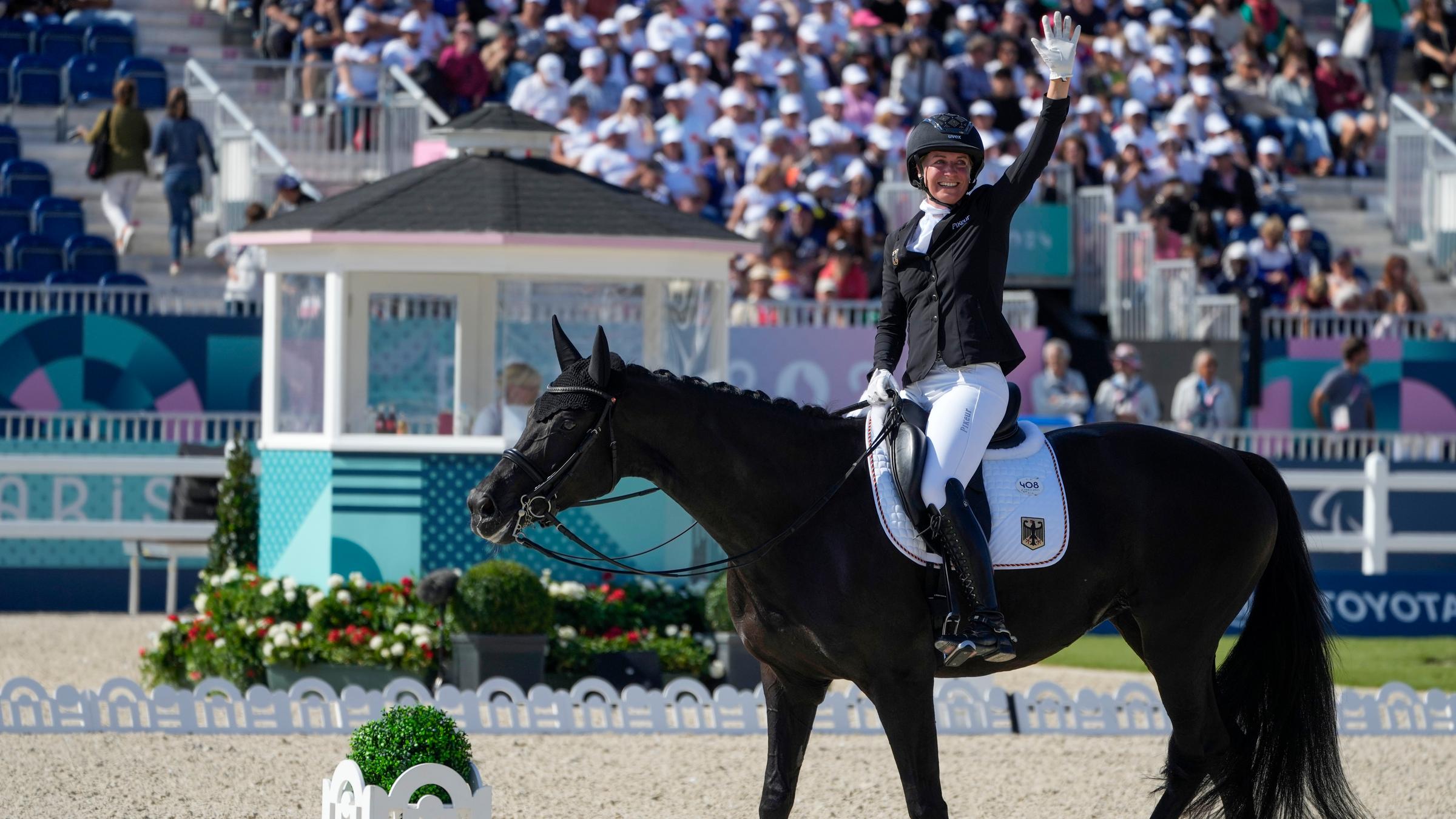 Anna-Lena Niehues sitzt auf ihrem Pferd und winkt dem Publikum zu.