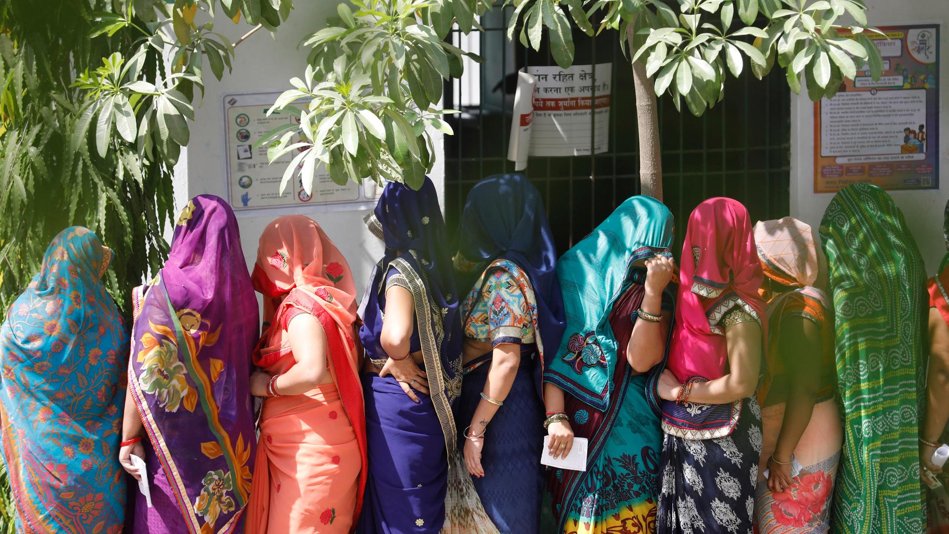 Indische Frauen stehen vor einem Wahllokal schlange.