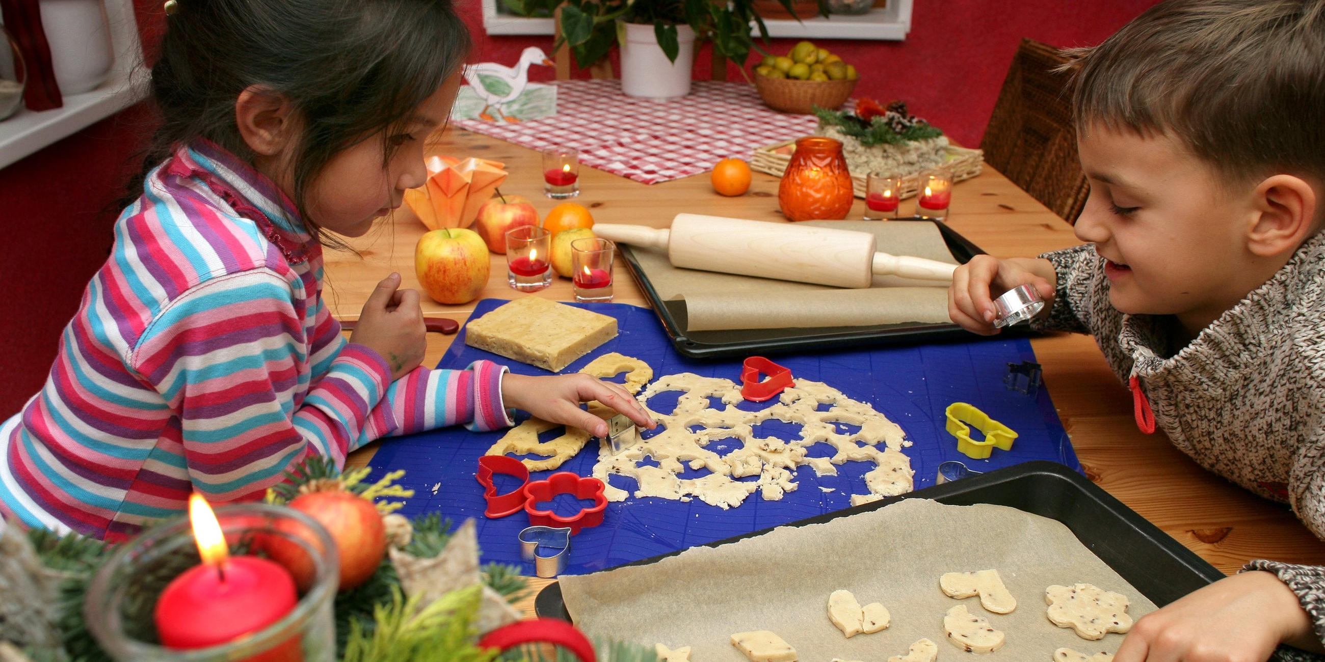 Kinder stechen Plätzchen aus.