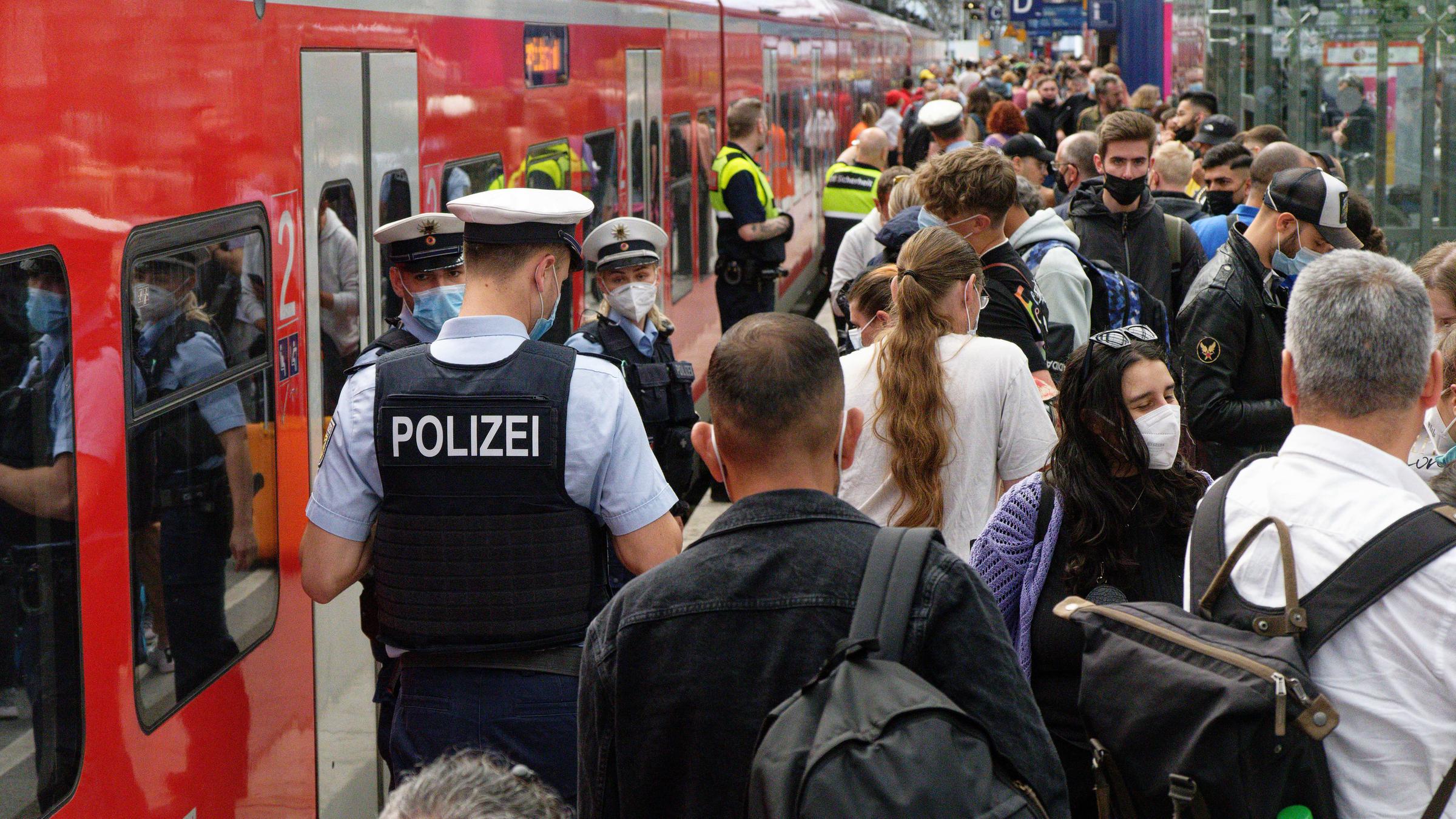 Polizei und Mitarbeiter der Deutschen Bahn weisen Reisenden auf einem überfülltem Bahnsteig im Hauptbahnhof den Weg.