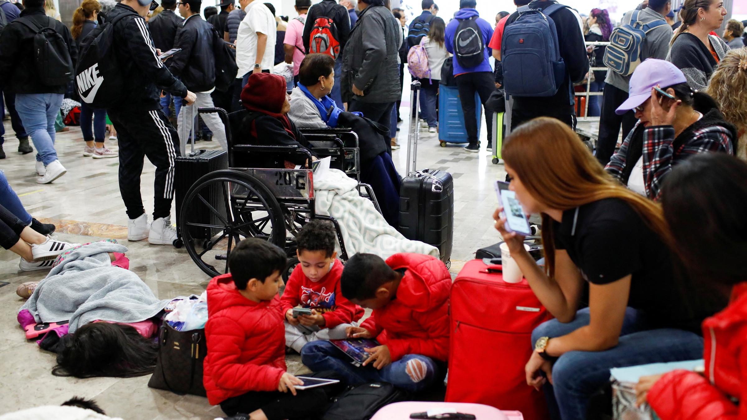 Eine Familie mit Koffern wartet an einem überfüllten Flughafen.