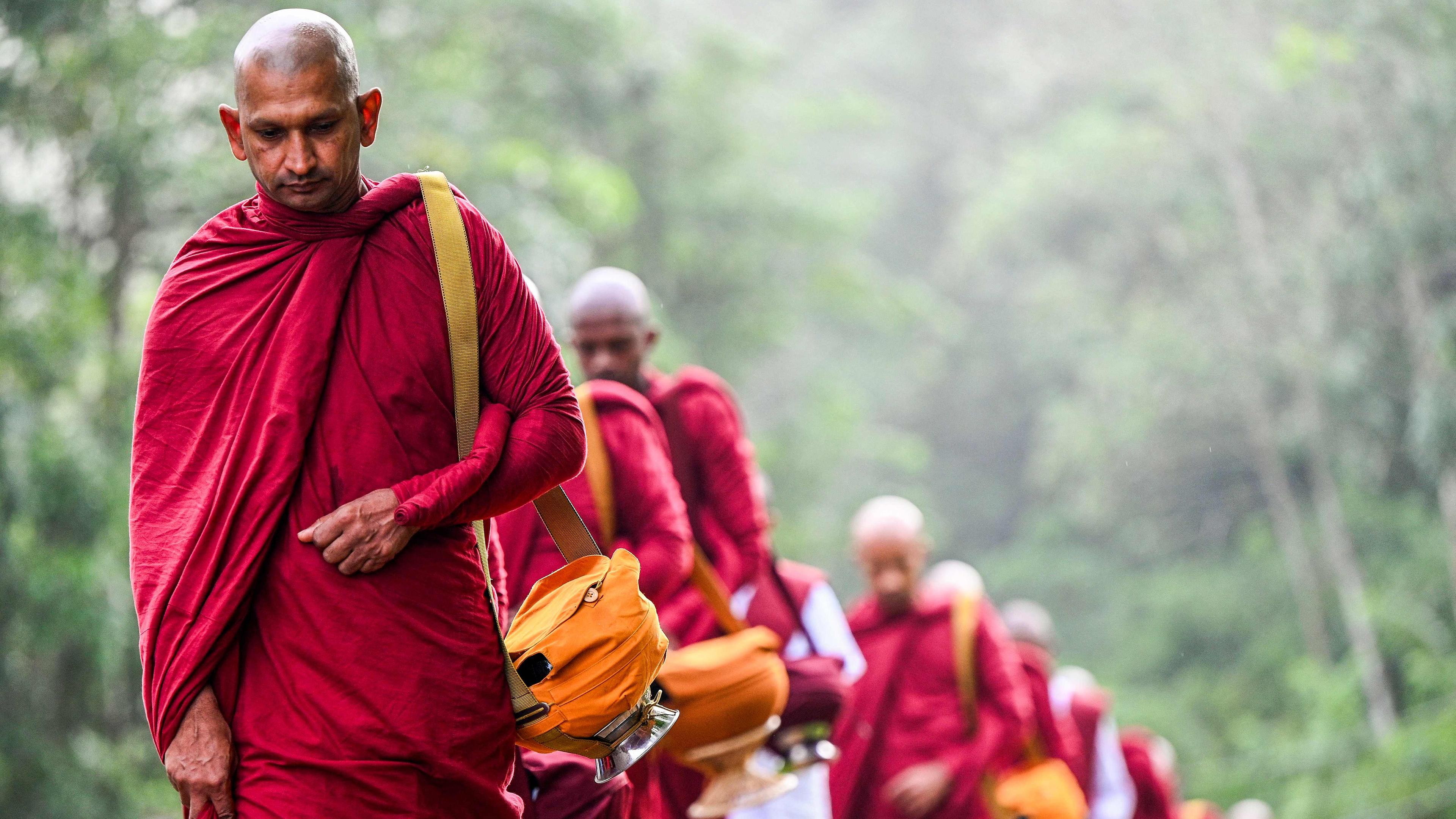 Mehrere buddhistische Mönche laufen hintereinander her