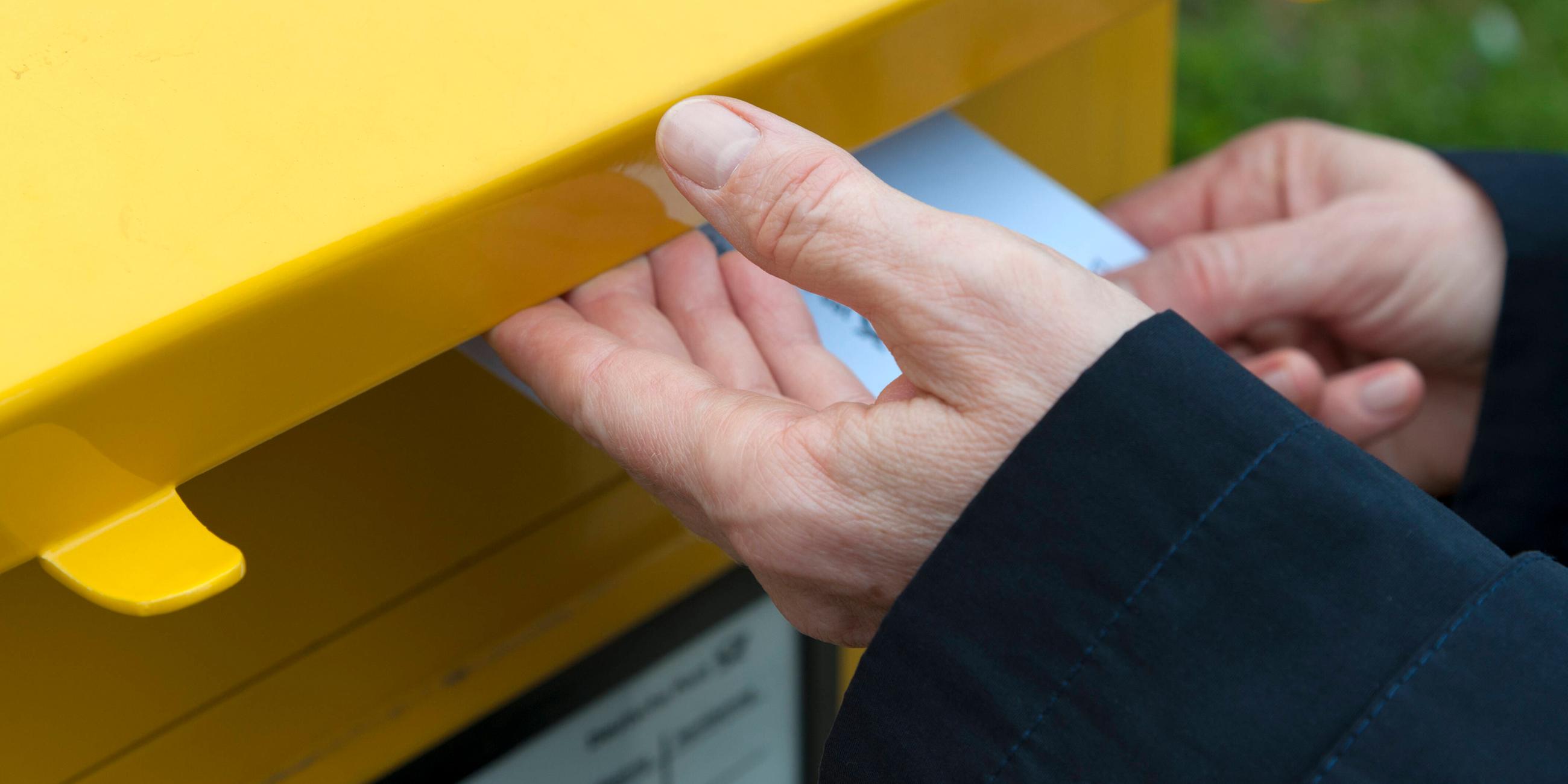 Mann wirft einen Brief in den Briefkasten