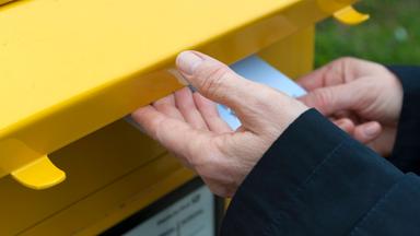 Mann wirft einen Brief in den Briefkasten