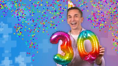 Eric mit Geburtstagshütchen, in der Hand hält er eine bunte 30. Hinter ihm fliegt Konfetti.