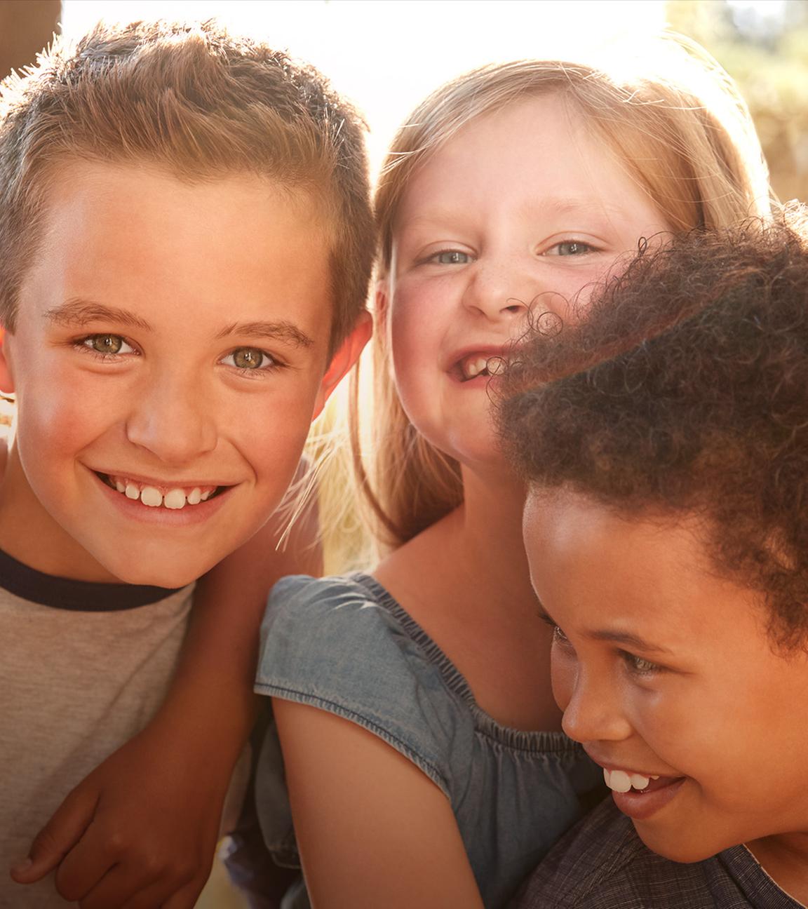 Es sind Kinder zu sehen, die in die Kamera lachen