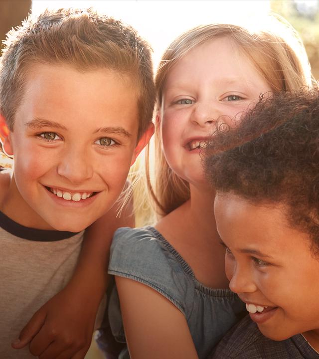 Es sind Kinder zu sehen, die in die Kamera lachen