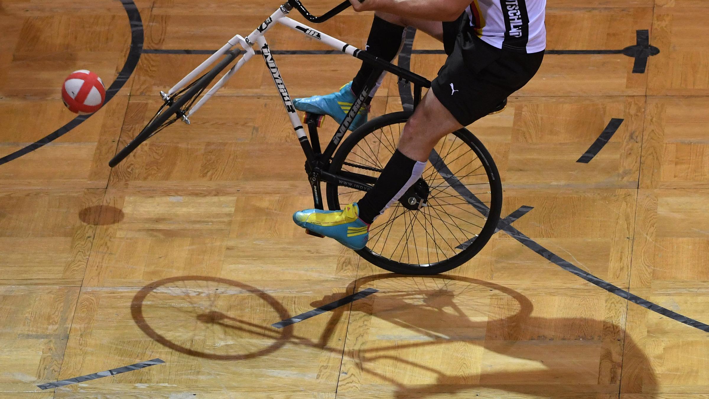Eine Person kickt einen Ball mit einem Fahrrad