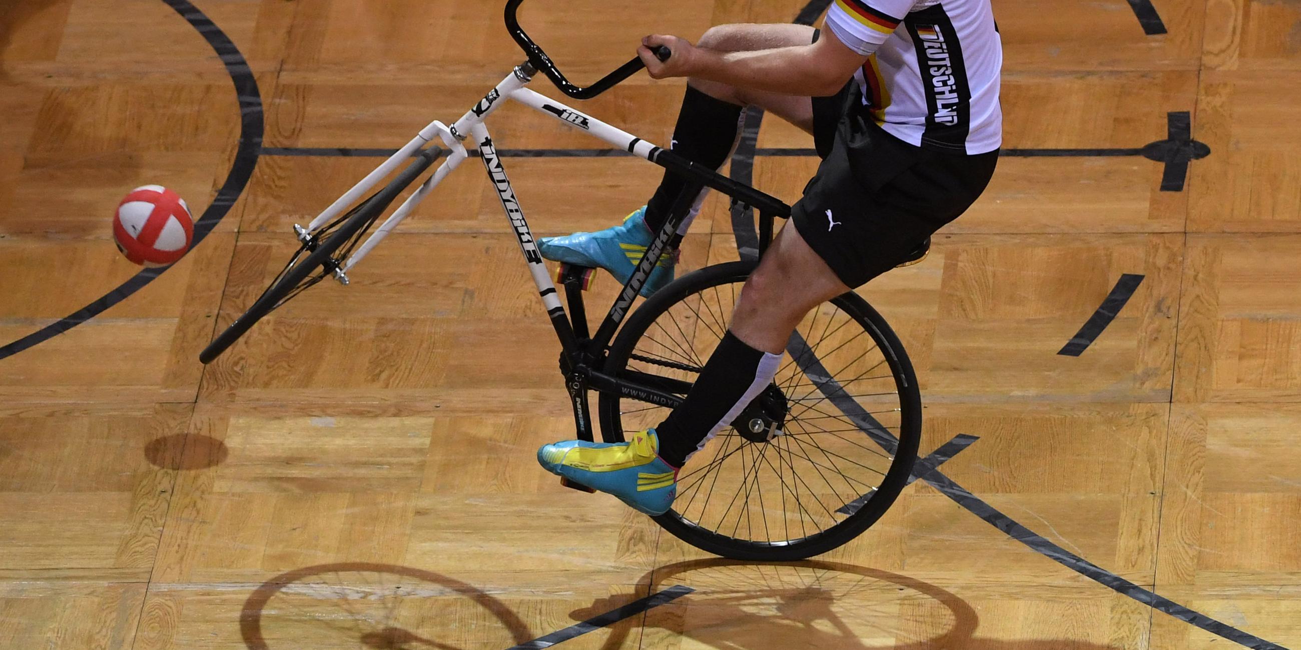 Eine Person kickt einen Ball mit einem Fahrrad