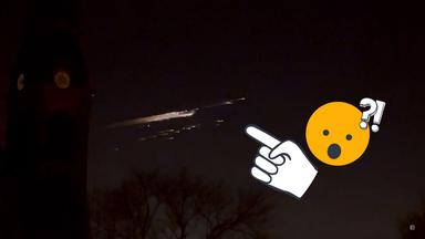 Raketentrümmer erleuchten Nachthimmel, ein Smiley schaut erstaunt, daneben ein Finger, der auf den Leuchtstreifen schaut und ein Fragezeichen und Ausrufezeichen