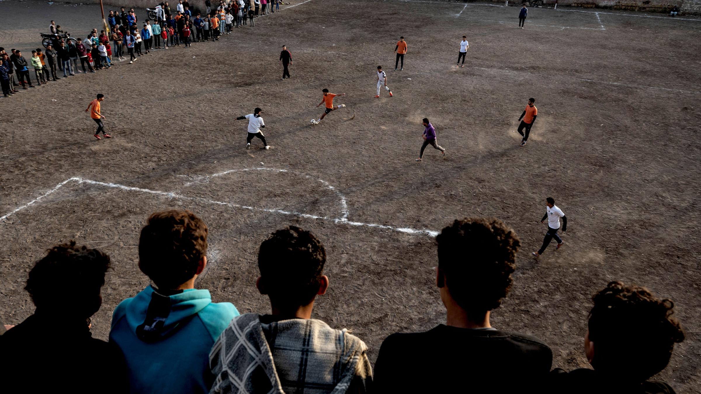 Ein paar Jungs sehen von einer erhöhten Position bei einem Fußballspiel zu.