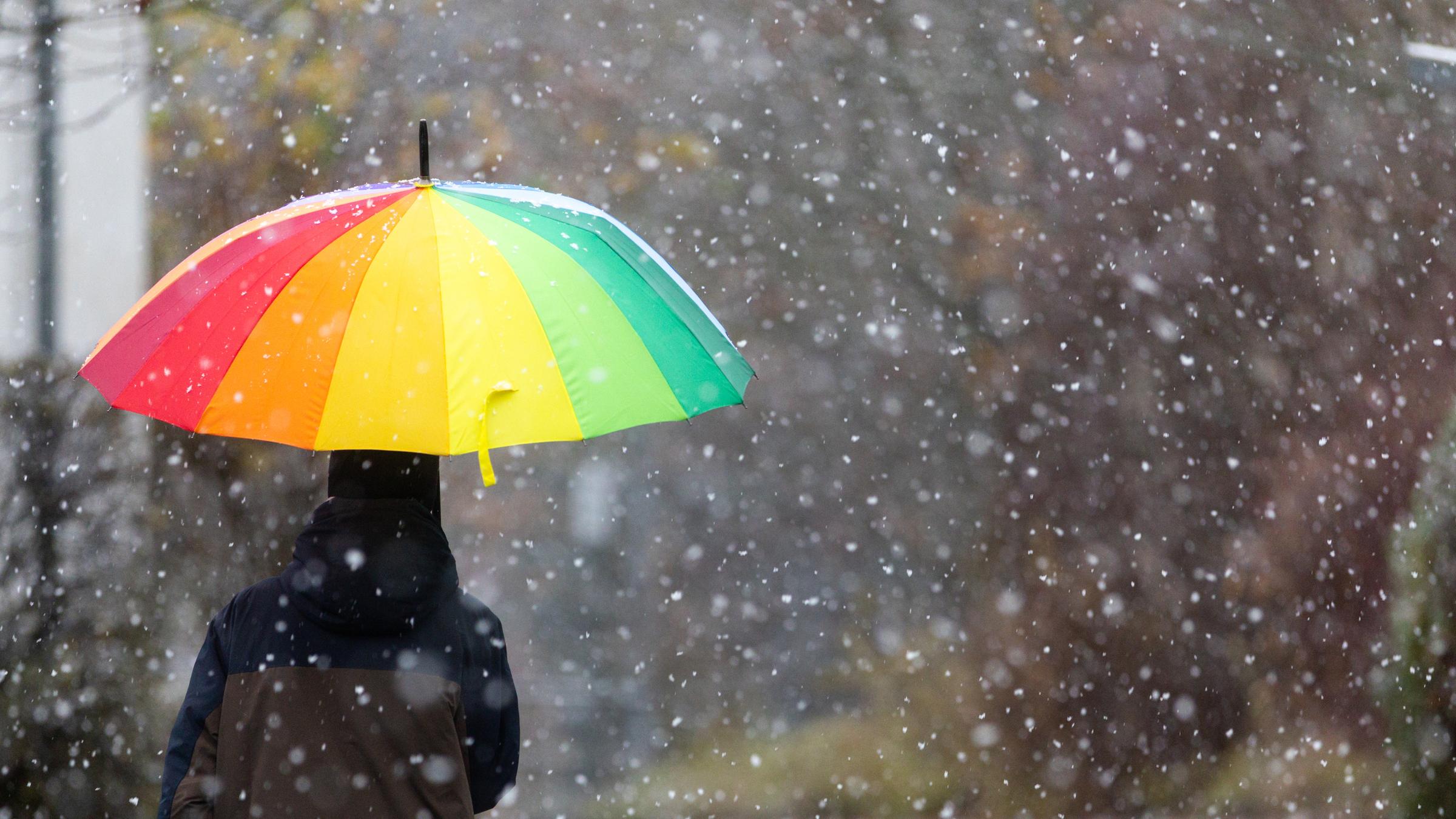 Ein Kind schützt sich mit einem Regenschirm vor Schneefall.