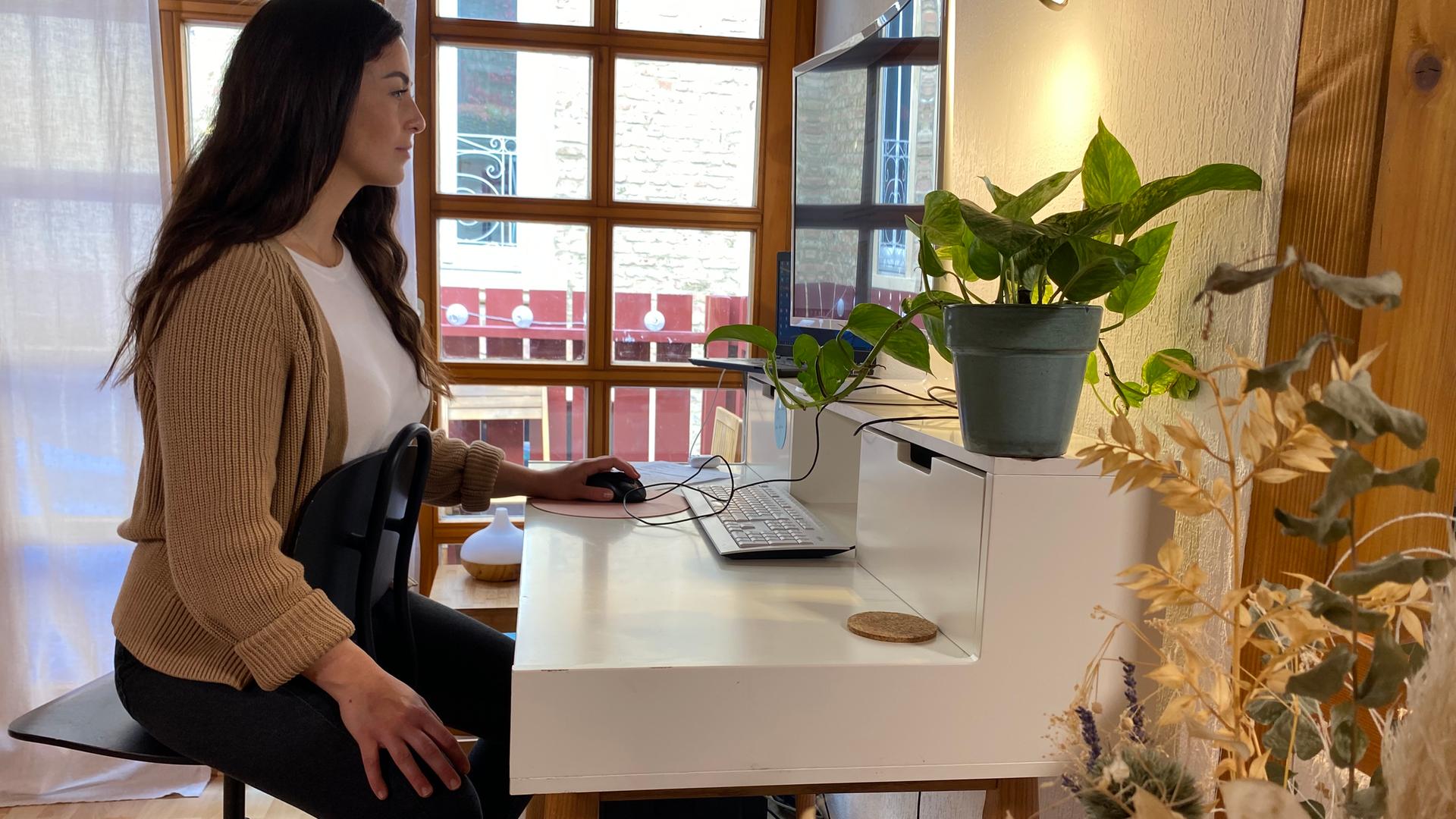 Teresa sitzt am Schreibtisch auf einem Stuhl mit der Lehne vorne. 
