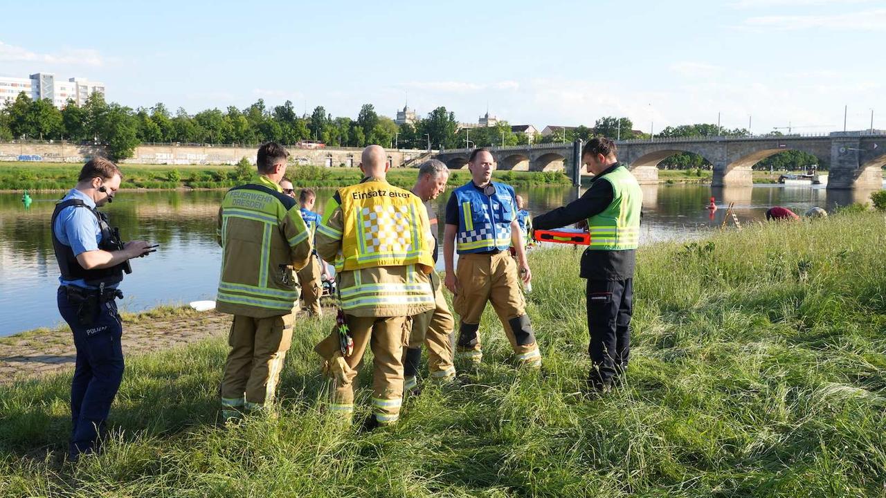 Rettungskräfte stehen am Elbufer in Dresden.