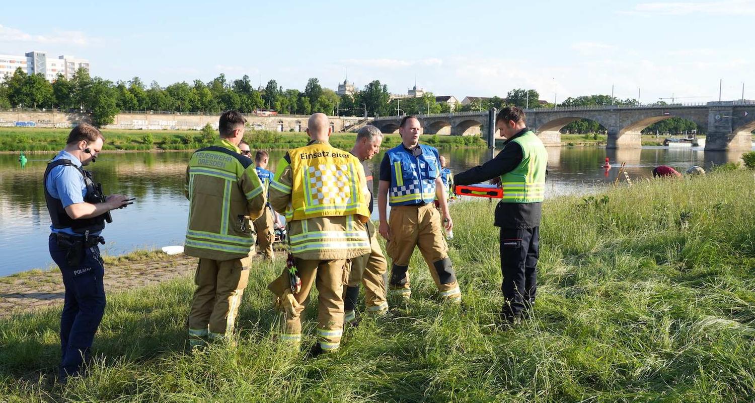 Rettungskräfte stehen am Elbufer in Dresden.