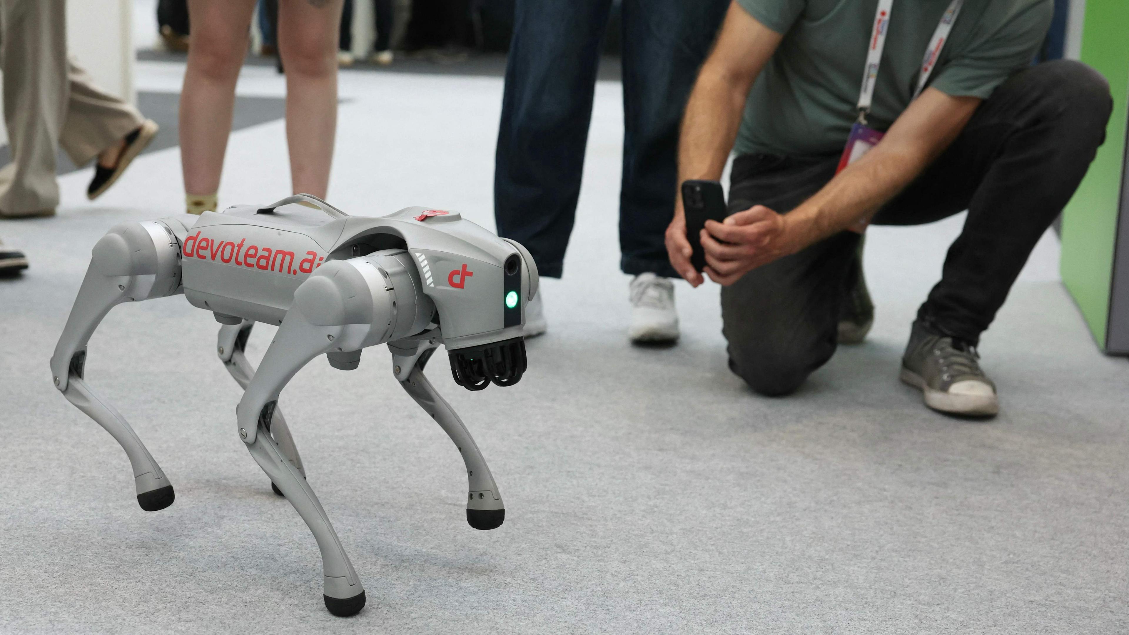 Ein Roboterhund wird von einem Besucher der Messe fotografiert