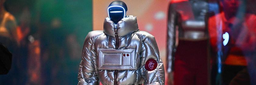 Bei einer Show in Seoul läuft ein modisch gekleideter Roboter in silberner Jacke über die Bühne. 