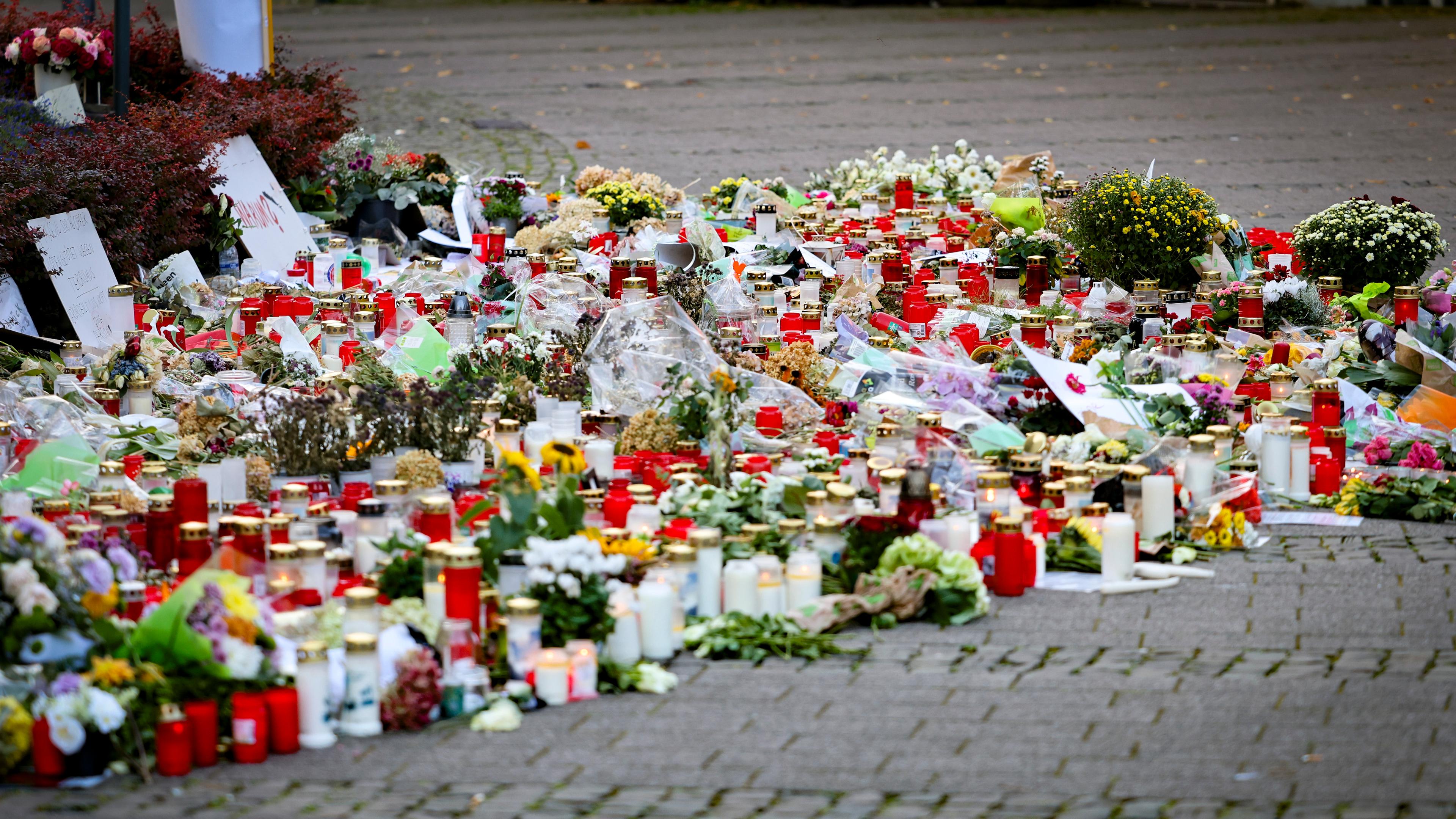 Kerzen und Blumen liegen zum Gedenken an die Opfer am Straßenrand.