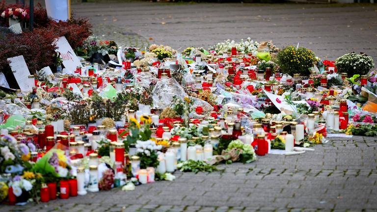 Kerzen und Blumen liegen zum Gedenken an die Opfer am Straßenrand.