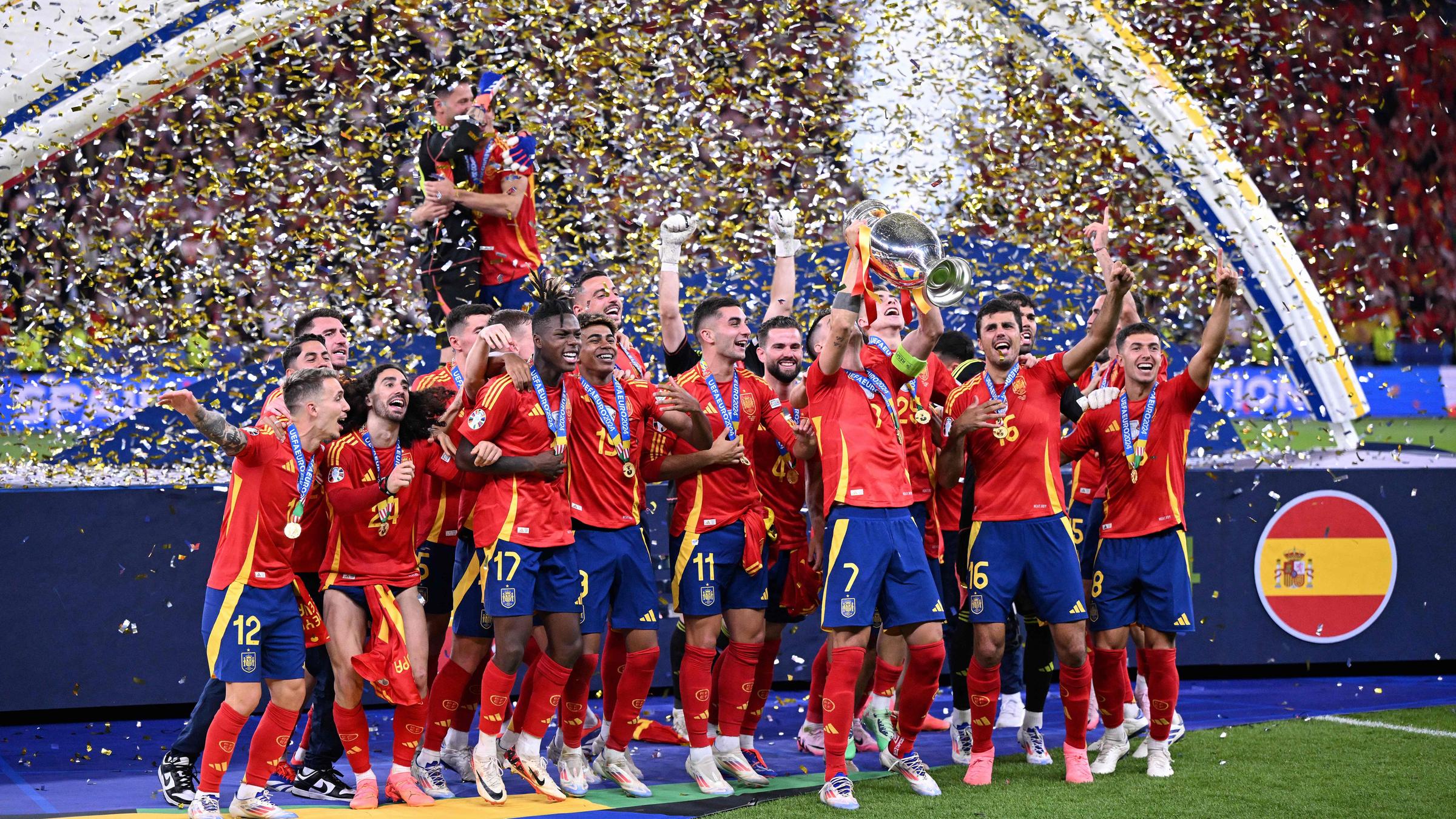 Das spanische Fußball-National-Team steht vor einer dunkelblauen Bühne im Konfetti-Regen und lässt sich als Europameister feiern.