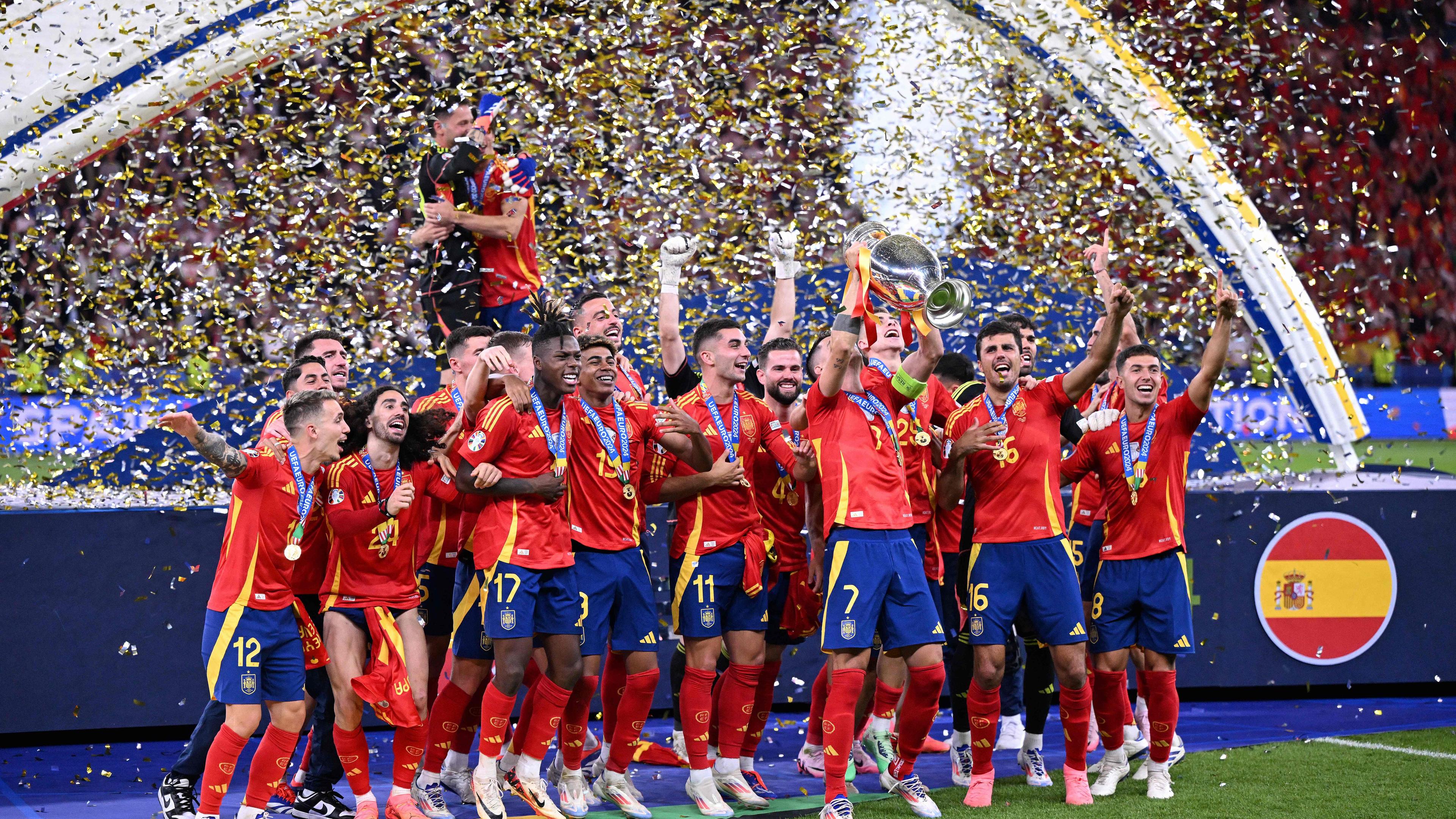 Das spanische Fußball-National-Team steht vor einer dunkelblauen Bühne im Konfetti-Regen und lässt sich als Europameister feiern.