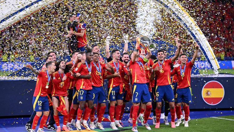 Das spanische Fußball-National-Team steht vor einer dunkelblauen Bühne im Konfetti-Regen und lässt sich als Europameister feiern.