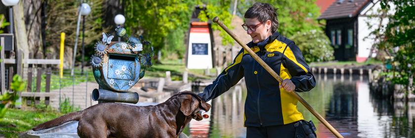 Postbotin übergibt Hündin Ronja die Zeitung. Sie liefert die Post übers Wasser im Spreewald aus.