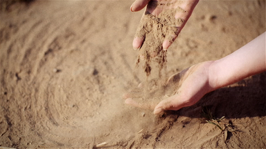 Sand rieselt durch die Finger zweier Hände