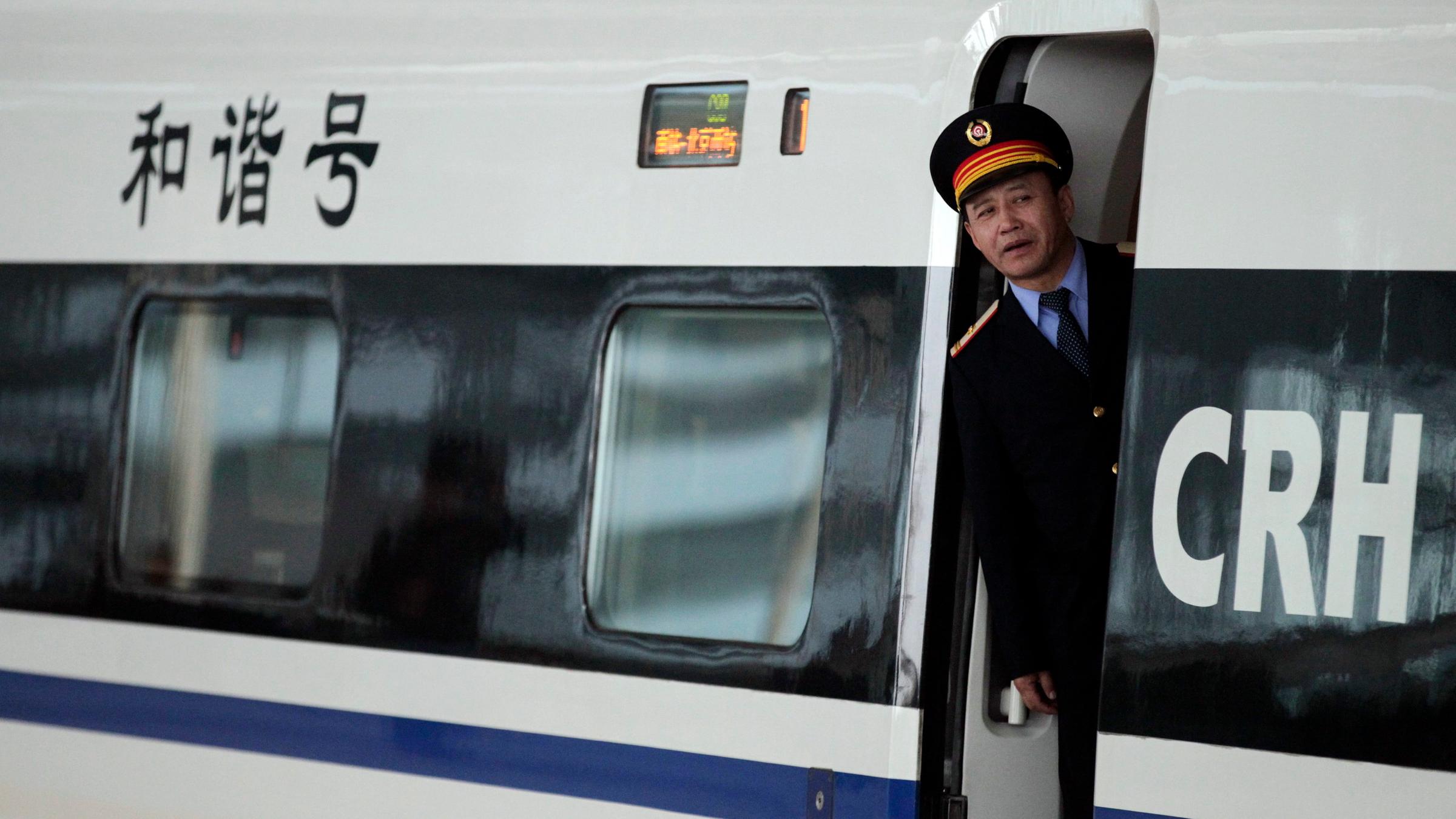 Ein chinesischer Schaffner schaut aus dem Zug.