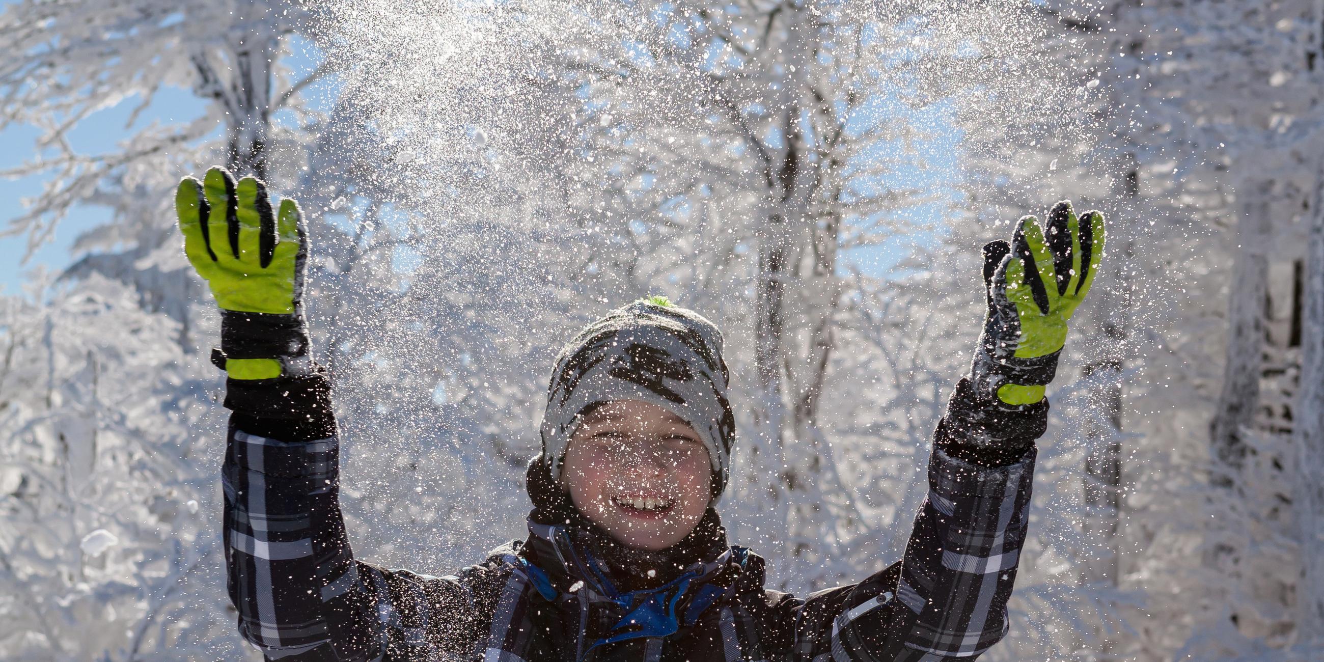 Mädchen pustet in Pulverschnee
