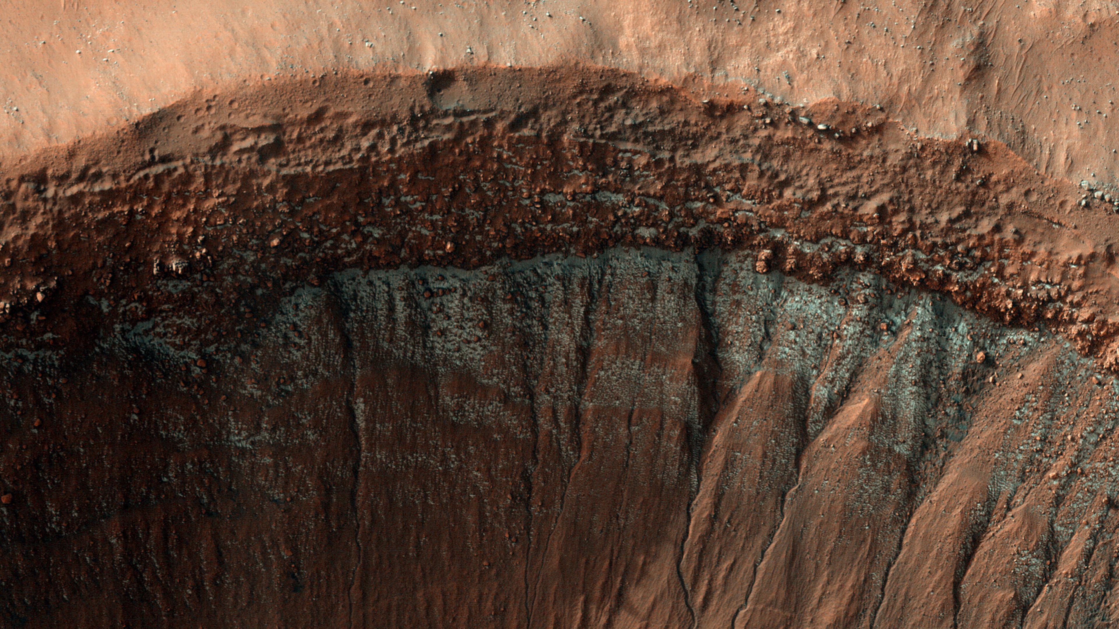 Die HiRISE-Kamera auf dem Mars Reconnaissance Orbiter zeigt kleine Trockeneisflecken nahe dem Äquator an den polzugewandten Hängen, die kälter sind, weil sie weniger Sonnenlicht erhalten. Dieses Bild wurde mitten im Winter auf der Südhalbkugel des Mars aufgenommen und zeigt einen Krater nahe dem 37. Grad südlicher Breite. Der nach Süden ausgerichtete Hang ist fleckig mit hellem Frost und verstärkter blauer Farbe versehen.