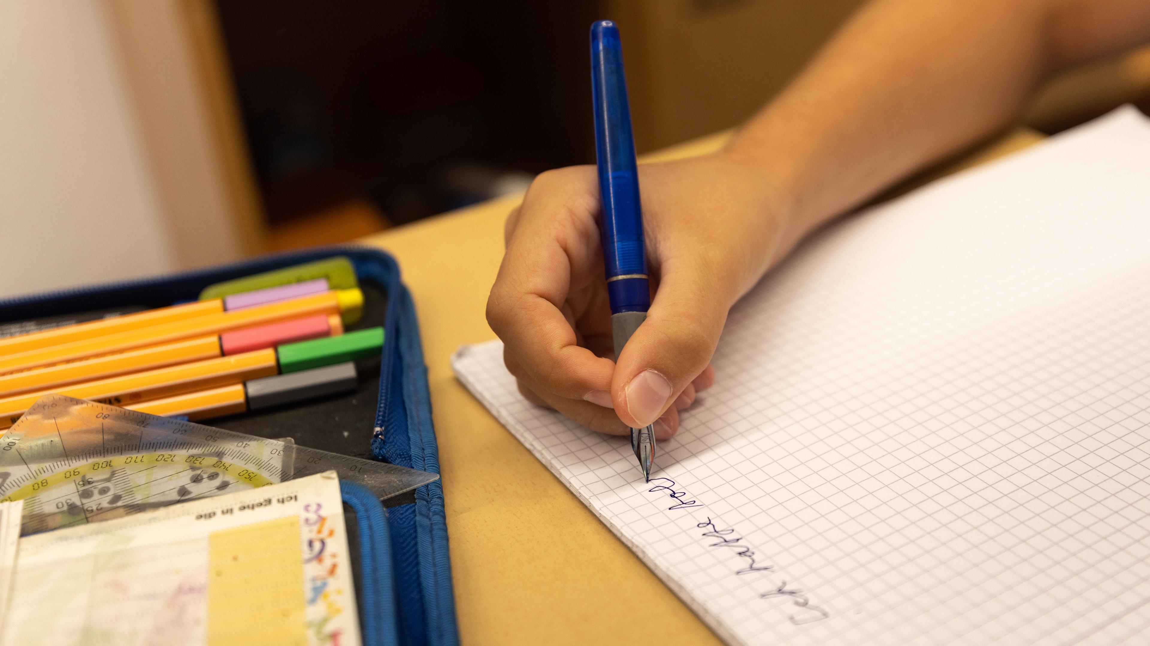 Ein Schüler der 6. Klasse schreibt in ein Heft an der Theodor Heuss-Realschule am ersten Schultag nach den Sommerferien.