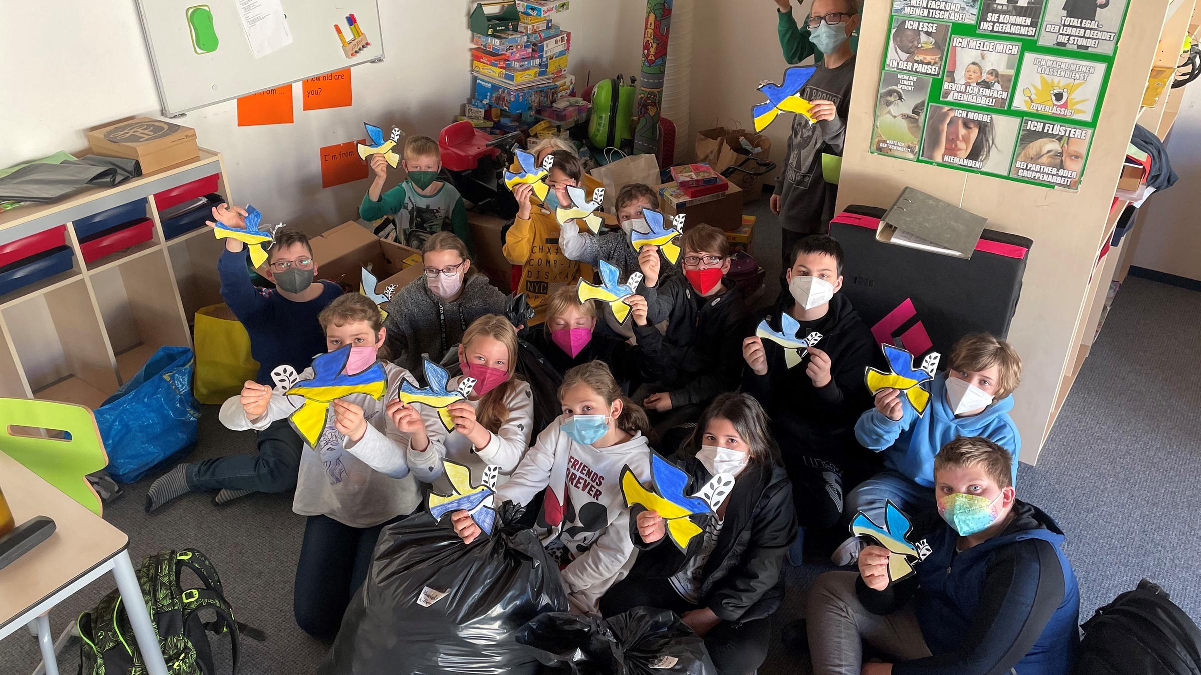 Schulklasse zeigt gebastelte Friedenstauben