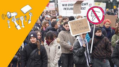Schülerinnen und Schüler demonstrieren mit Pappschildern in Hamburg.