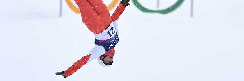 Die Schweizer Freestyle-Skifahrerin Lina Kozomara springt bei den Winterspielen spektakulär kopfüber durch die Luft – vor den Olympischen Ringen.