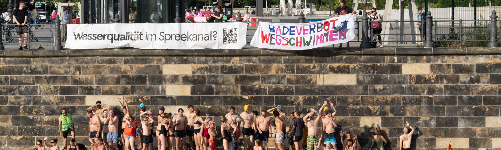 Demonstrationsteilnehmer und Teilnehmerinnen im Wasser und auf einem Schwimmponton.