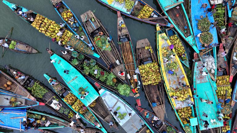 Bei einem schwimmenden Markt in Bangladesch verkaufen Bauern auf ihren Booten Obst und Gemüse.