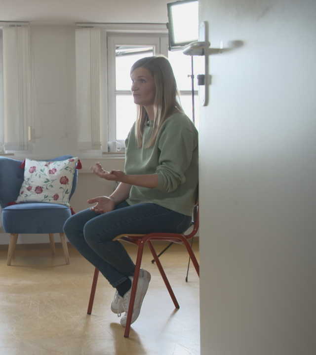Simone und eine Frau sitzen sich auf zwei Stühlen gegenüber
