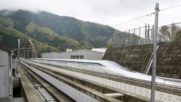 Ein weißer Zug fährt in einer Bahn aus Beton