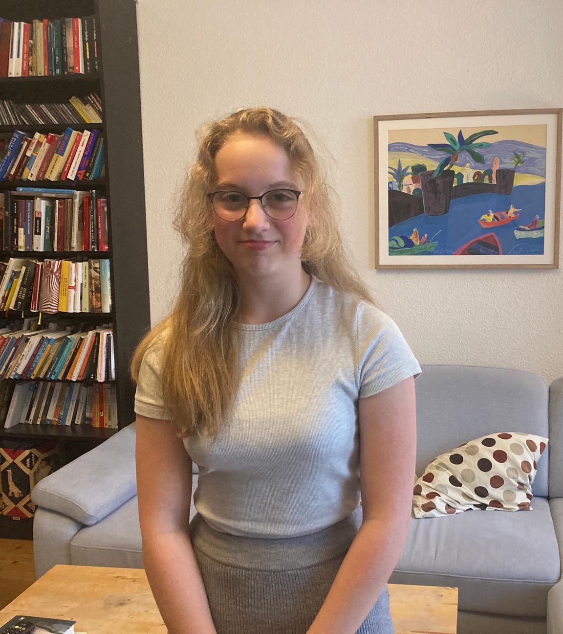 EIn Mädchen steht im Wohnzimmer und lächelt vorsichtig. 
