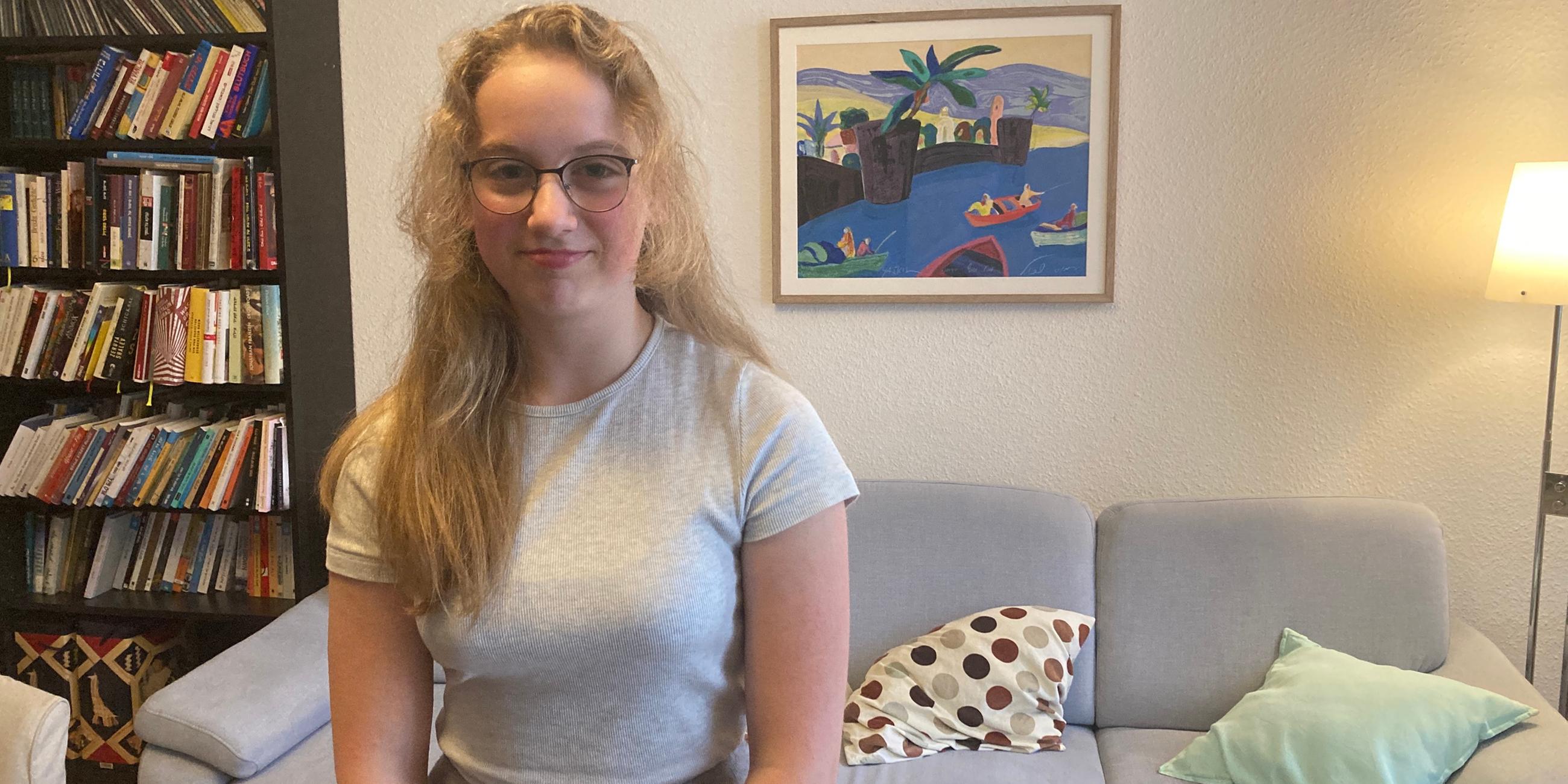 EIn Mädchen steht im Wohnzimmer und lächelt vorsichtig. 