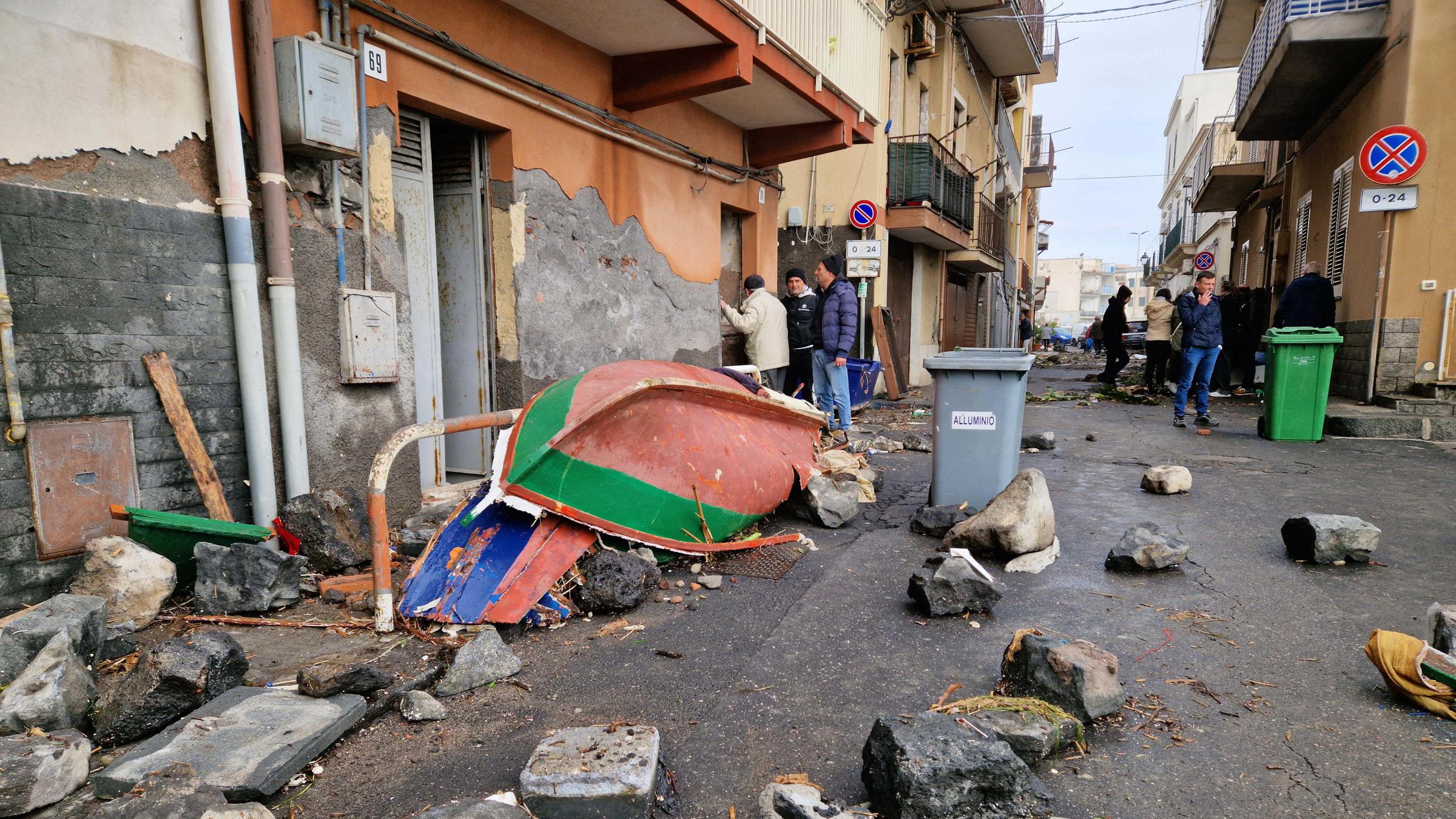 In der sizilianischen Stadt Aci Trezza herrscht Chaos: Steine und Boote liegen nach unwetter auf Straße. 