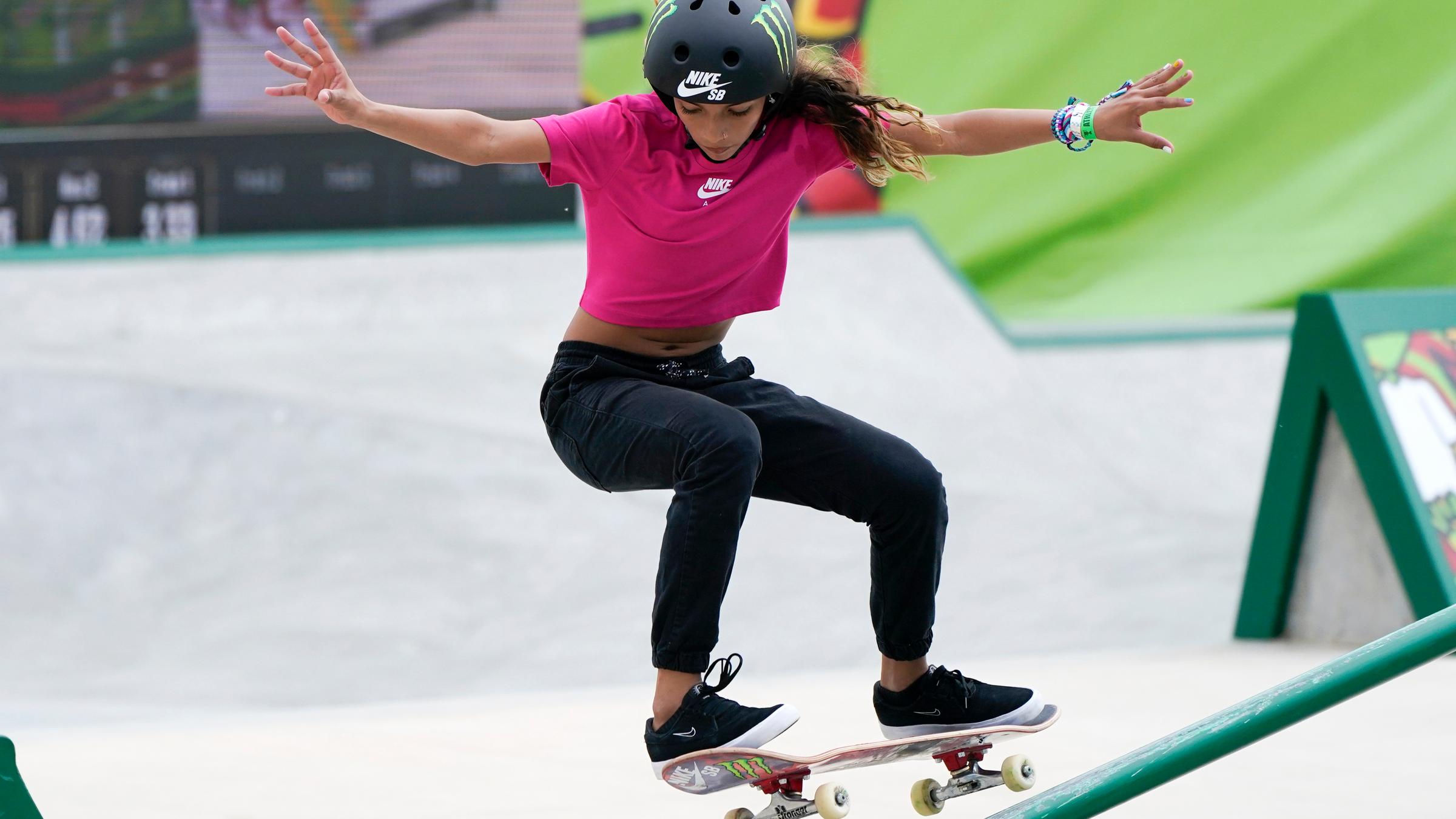 Eine Frau fährt Skateboard und versucht mit den Armen ihr Gleichgewicht zu halten.