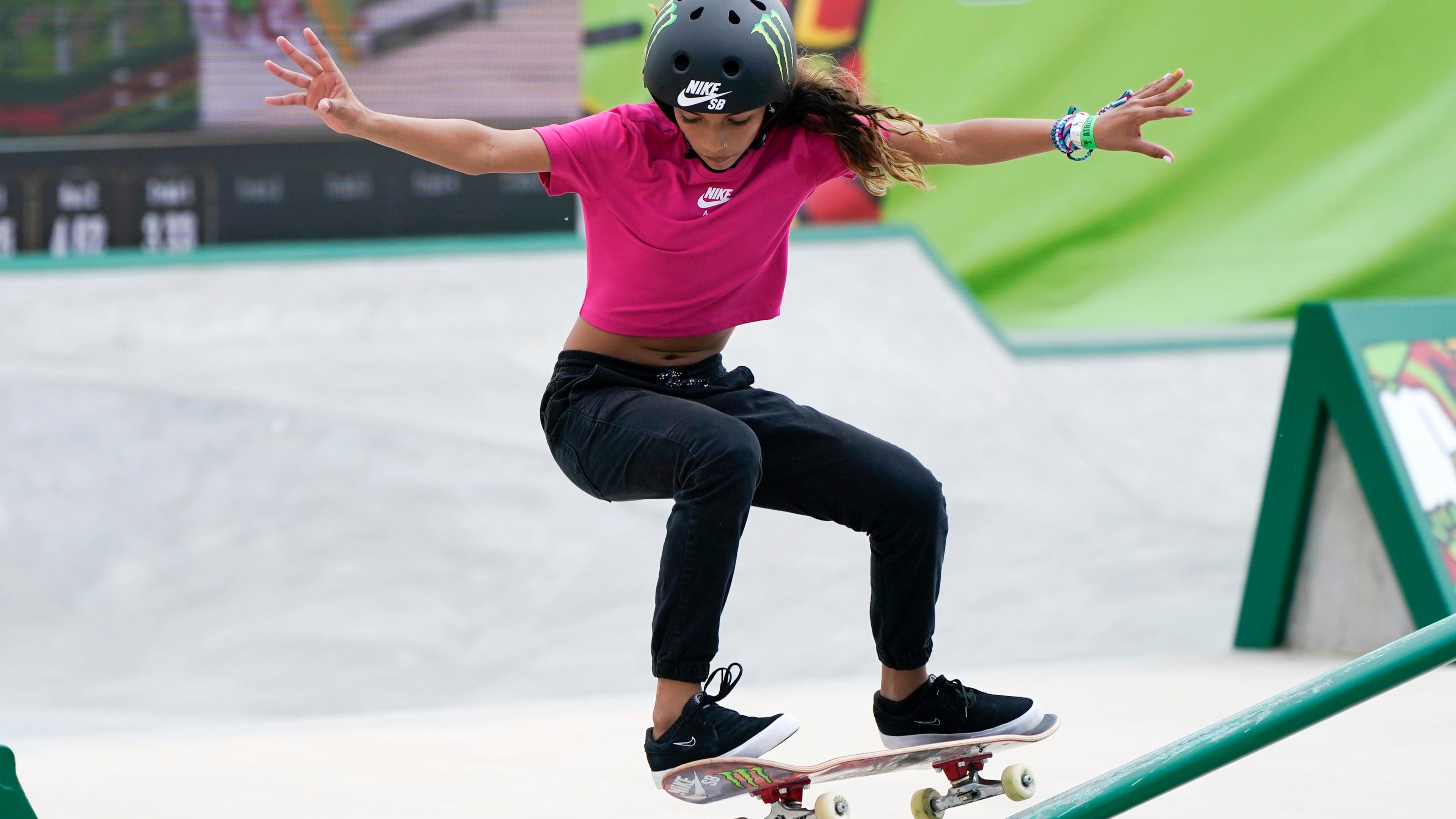 Eine Frau fährt Skateboard und versucht mit den Armen ihr Gleichgewicht zu halten.