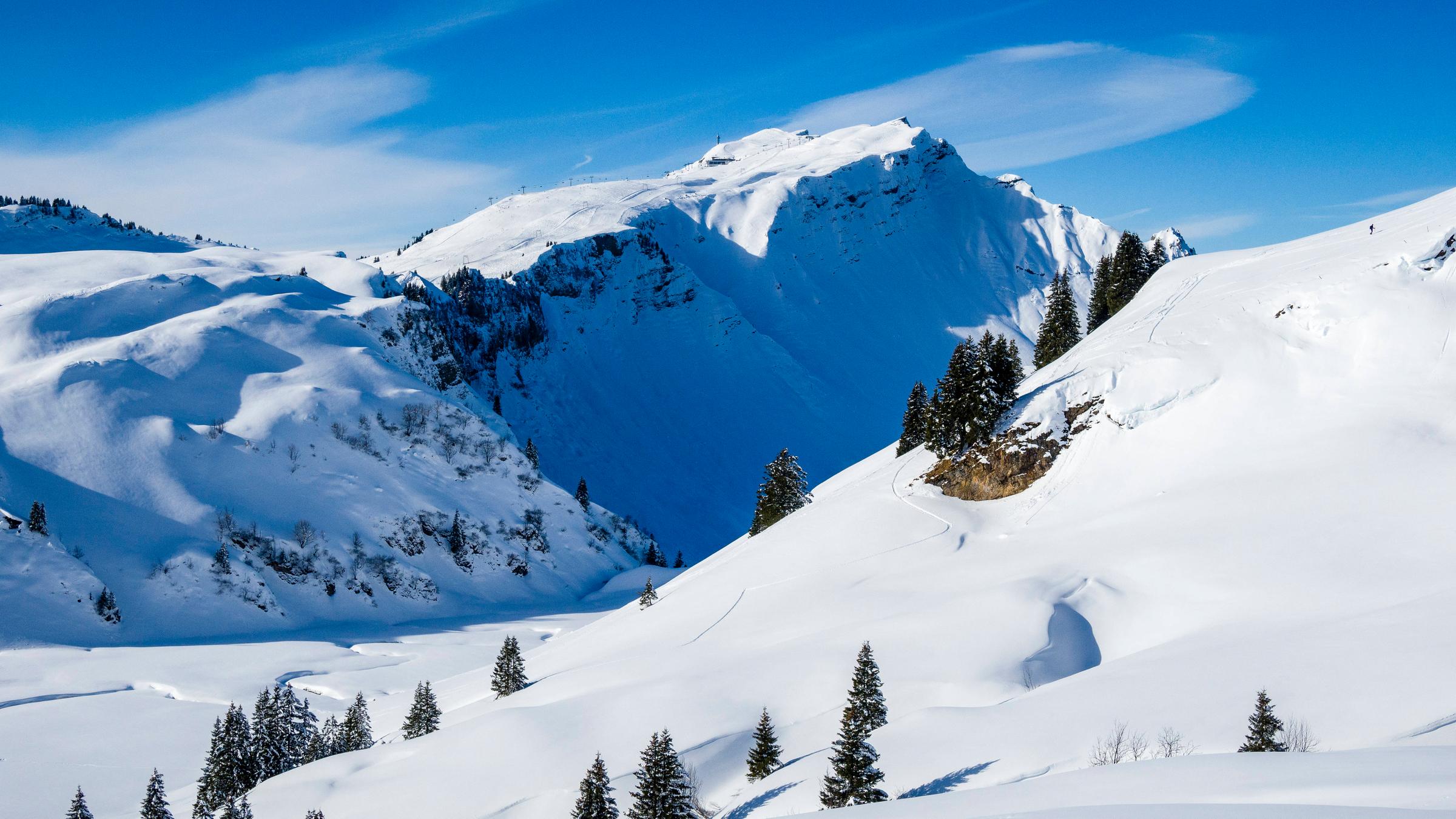 Ein schneebedekter Berg erhebt sich aus einem Gebirgsmassiv in den Alpen.