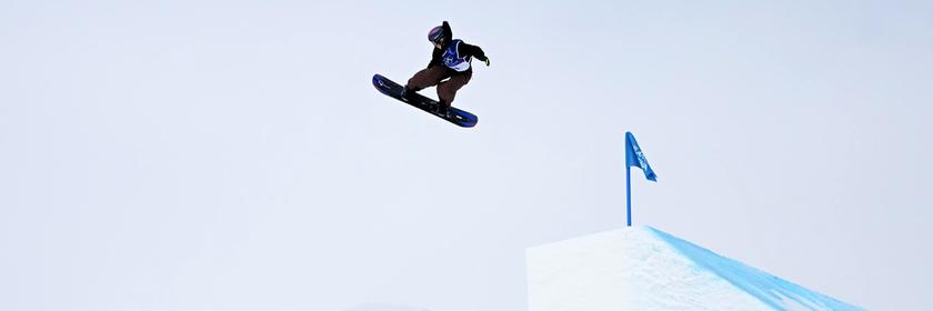 Snowboaderin fliegt nach einer Rampe auf der Piste 