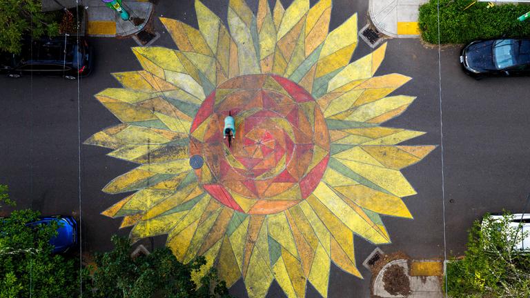 Eine große, gelbe Sonnenblume wurde auf eine Kreuzung gemalt. 