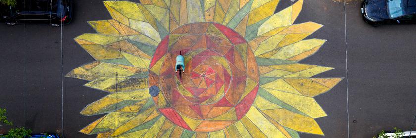 Eine große, gelbe Sonnenblume wurde auf eine Kreuzung gemalt. 